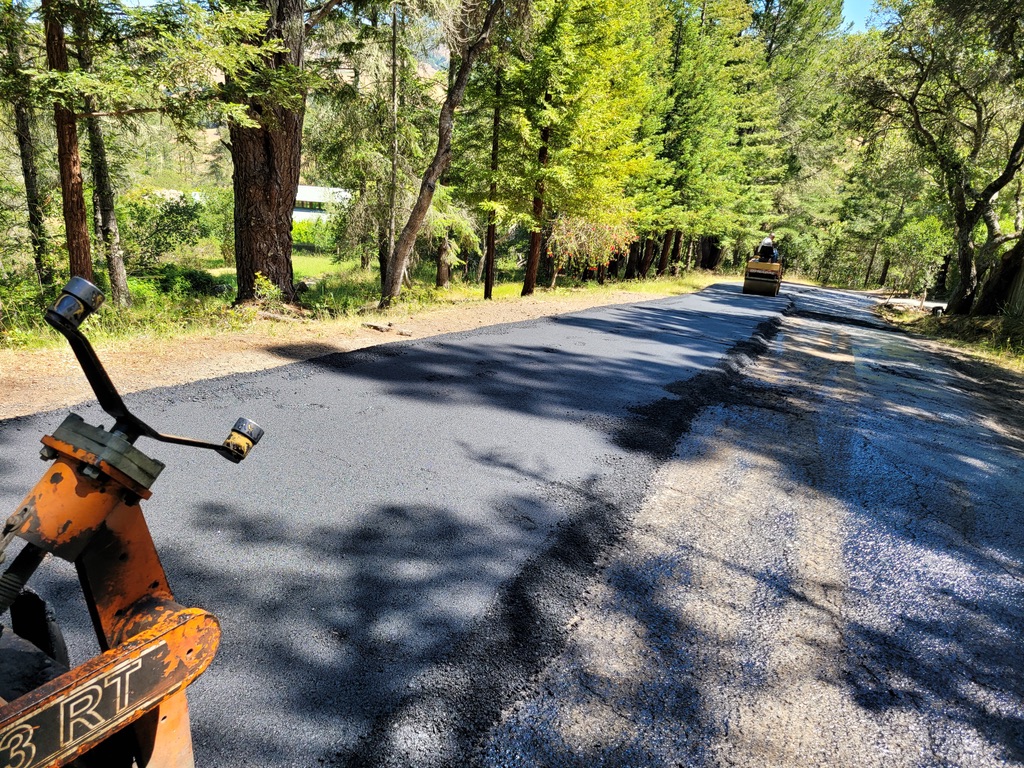 Fresh asphalt paving being compacted on a private road