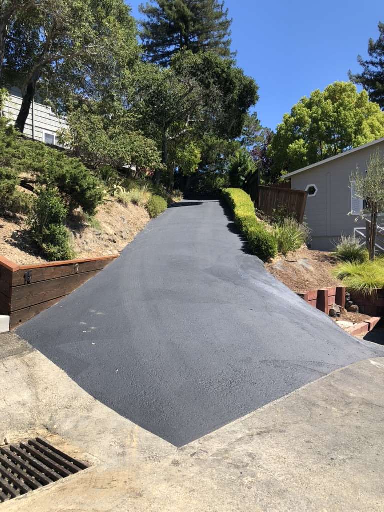 Freshly paved asphalt driveway on a residential hill