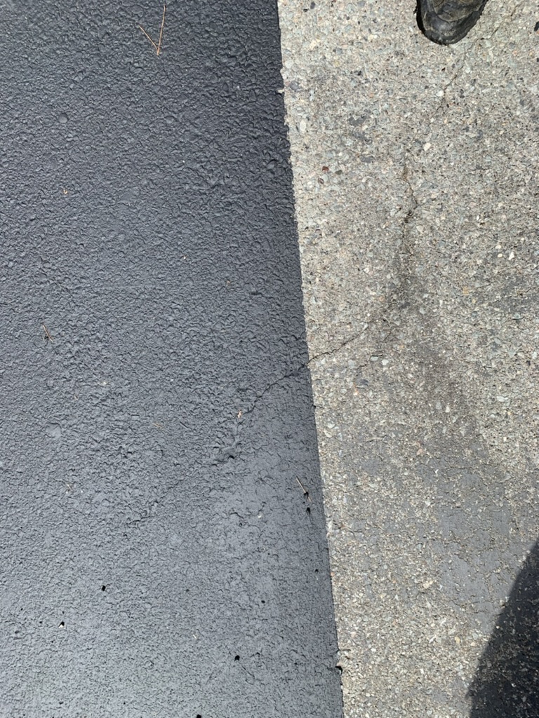 Close-up comparison of seal coated asphalt next to untreated asphalt