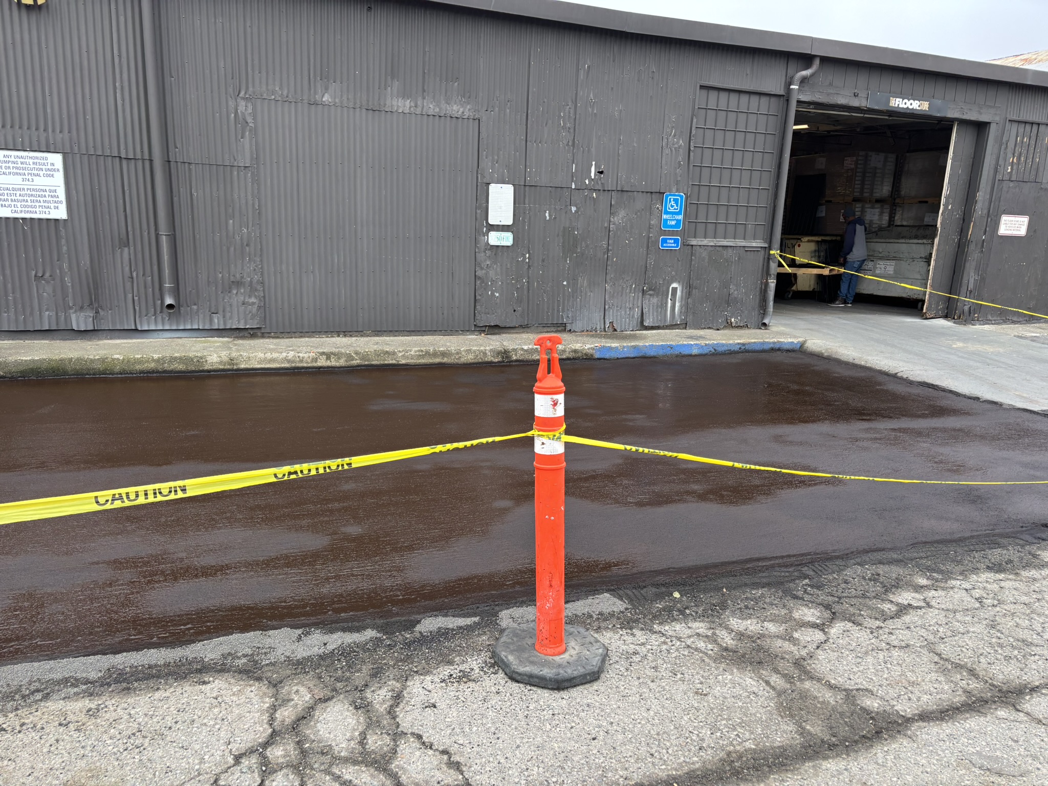 Wet brown slurry seal curing on a tree-lined private road